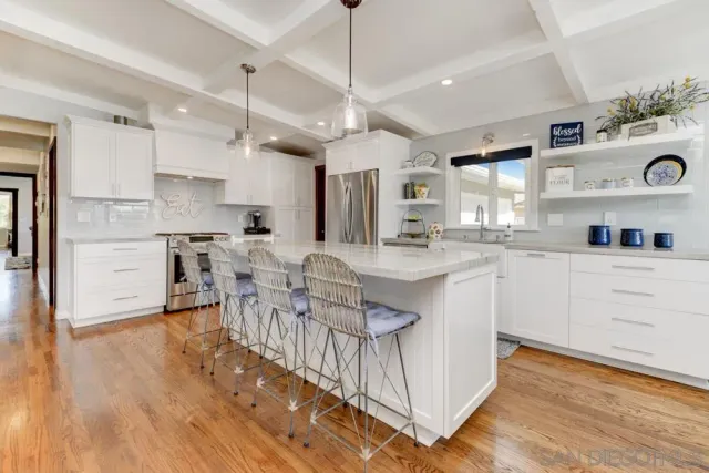 a kitchen with stainless steel appliances a dining table chairs sink and cabinets