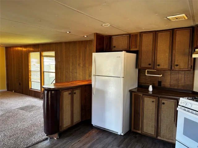 a kitchen with a refrigerator a stove top oven a sink and dishwasher with wooden floor