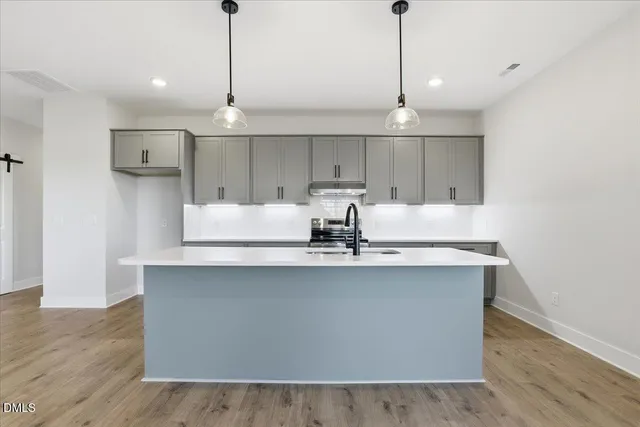 a kitchen with stainless steel appliances a sink a window a refrigerator and wooden floor