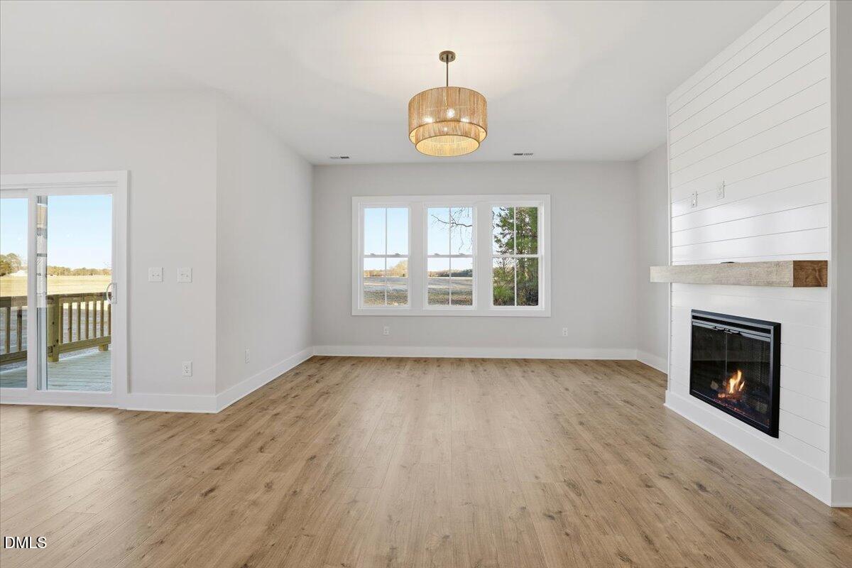 47 Gold Court Kenly, NC 27542 - Photo 6 of 32 an empty room with wooden floor fireplace and windows