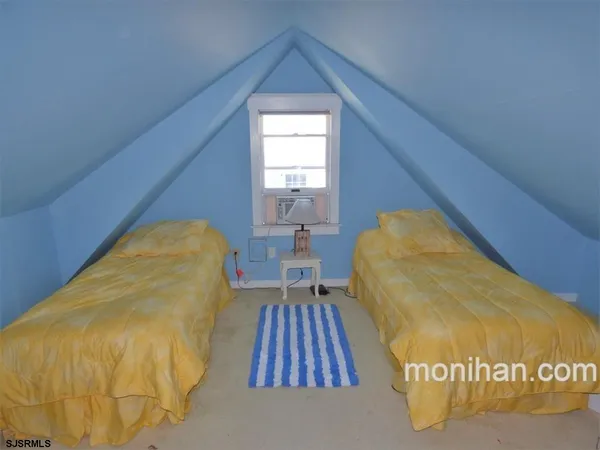 a view of a bedroom with wooden floor and a rug
