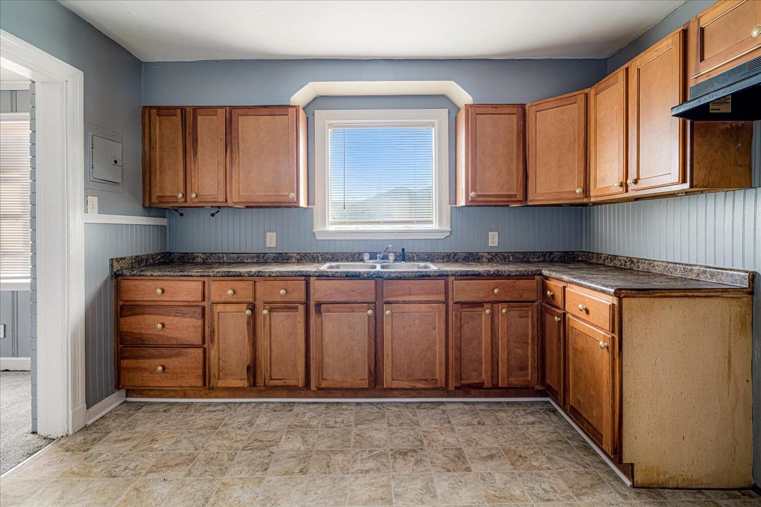 1114 Brownlee Road Memphis, TN 38116 - Photo 19 of 32 Kitchen featuring dark countertops, brown cabinetry, ventilation hood, wood walls, and electric panel