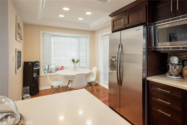 a kitchen with stainless steel appliances kitchen island granite countertop a refrigerator a stove and a sink with wooden floor