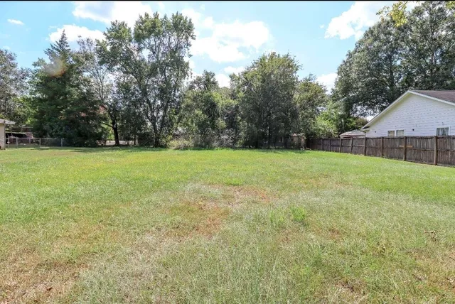 a view of a green field with trees in the background