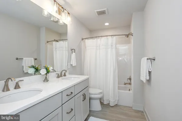 a bathroom with double vanity sink a mirror and a toilet