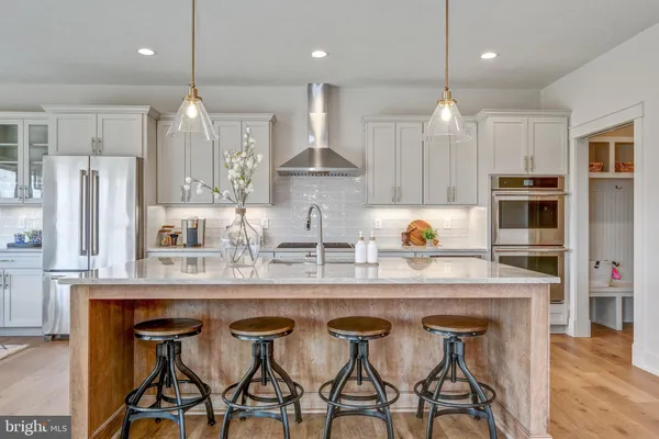 a kitchen with stainless steel appliances granite countertop a sink a stove a refrigerator and chairs