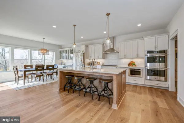 a kitchen with stainless steel appliances granite countertop a dining table chairs stove a refrigerator and cabinets