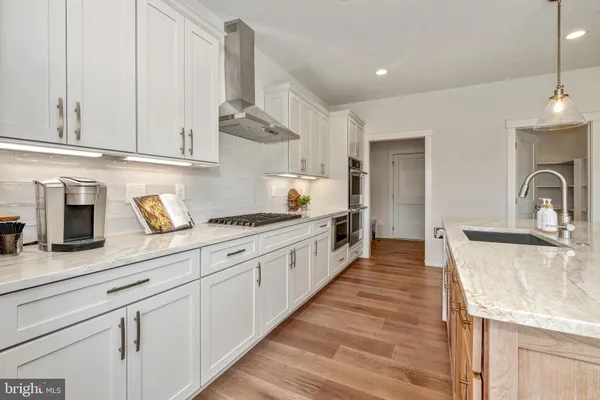 a large kitchen with stainless steel appliances granite countertop a lot of counter space and wooden floor