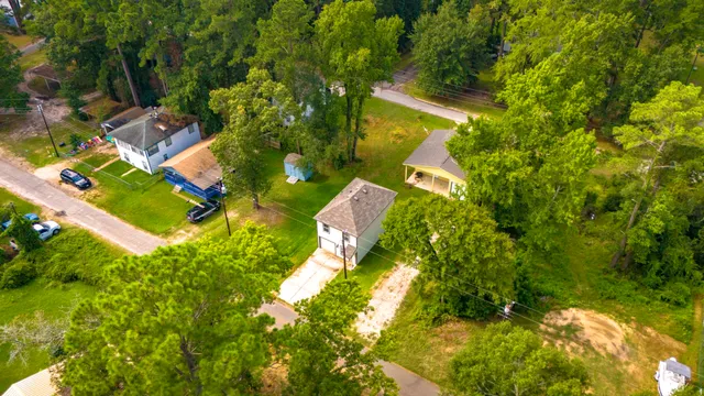 an aerial view of residential house with outdoor space and trees all around
