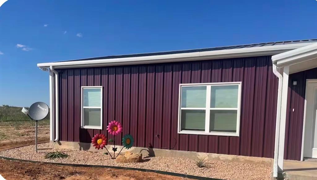 7565 Fm 3116 Anson, TX 79501 - Photo 2 of 15 Rich burgundy vertical panel siding with white trim and white gutters