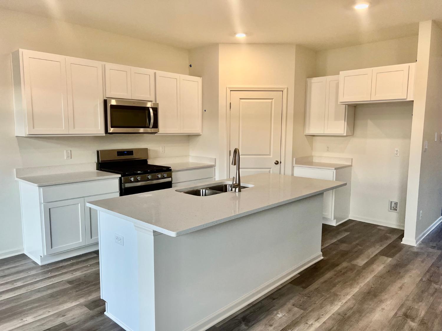 7718 West 103rd Street Crown Point, IN 46307 - Photo 9 of 47 a kitchen with stainless steel appliances a sink a stove a microwave a refrigerator a white counter top and cabinets