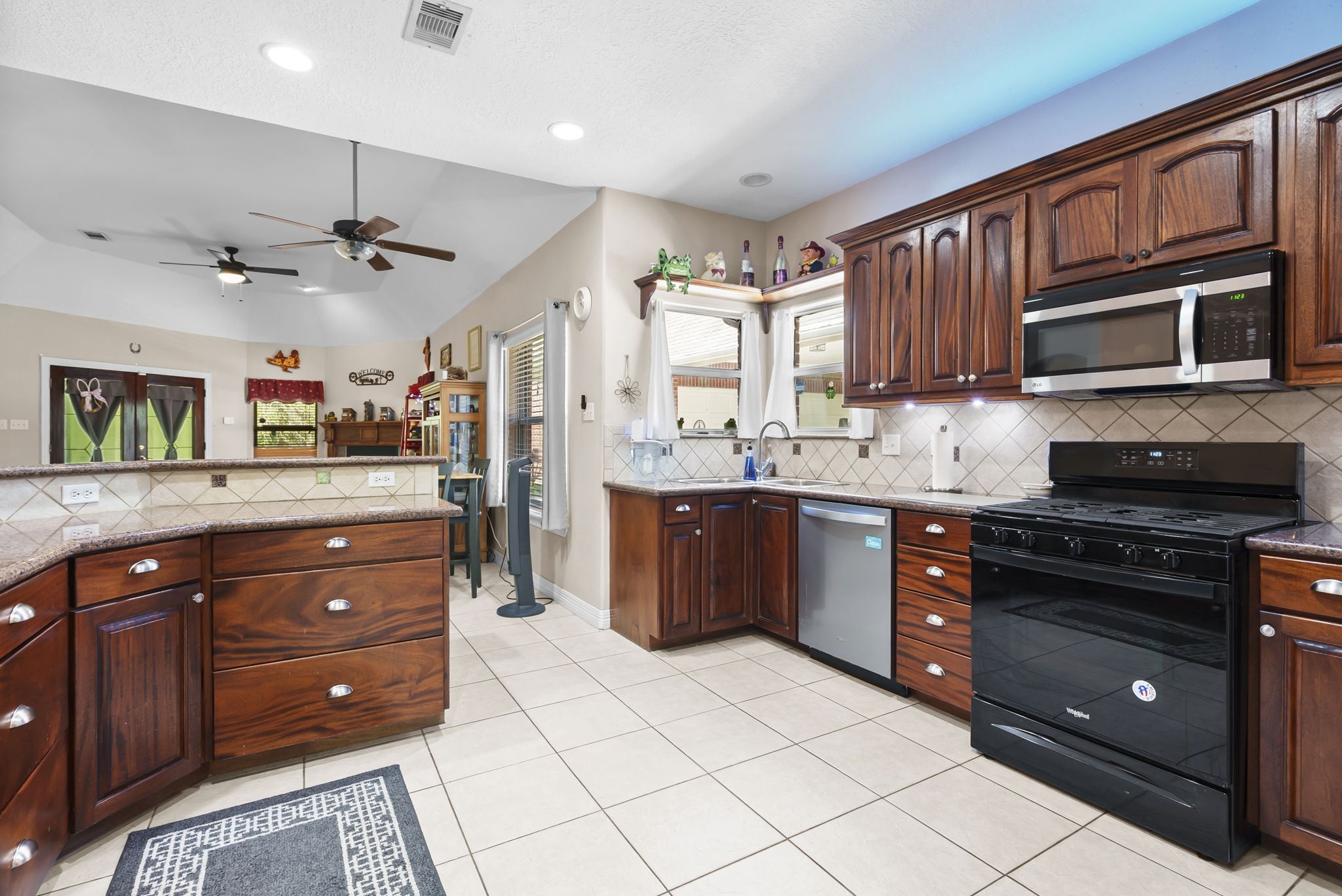 15524 Jim Branch Road Dayton, TX 77535 - Photo 22 of 40 a kitchen with stainless steel appliances granite countertop a stove a sink dishwasher and a microwave oven with wooden cabinets