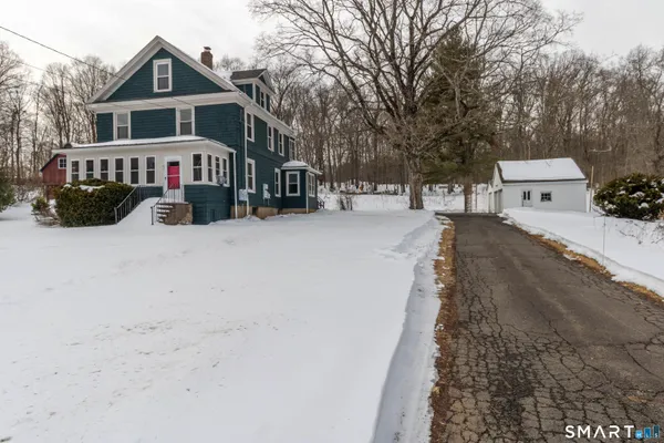 a view of a white house with a yard covered in snow
