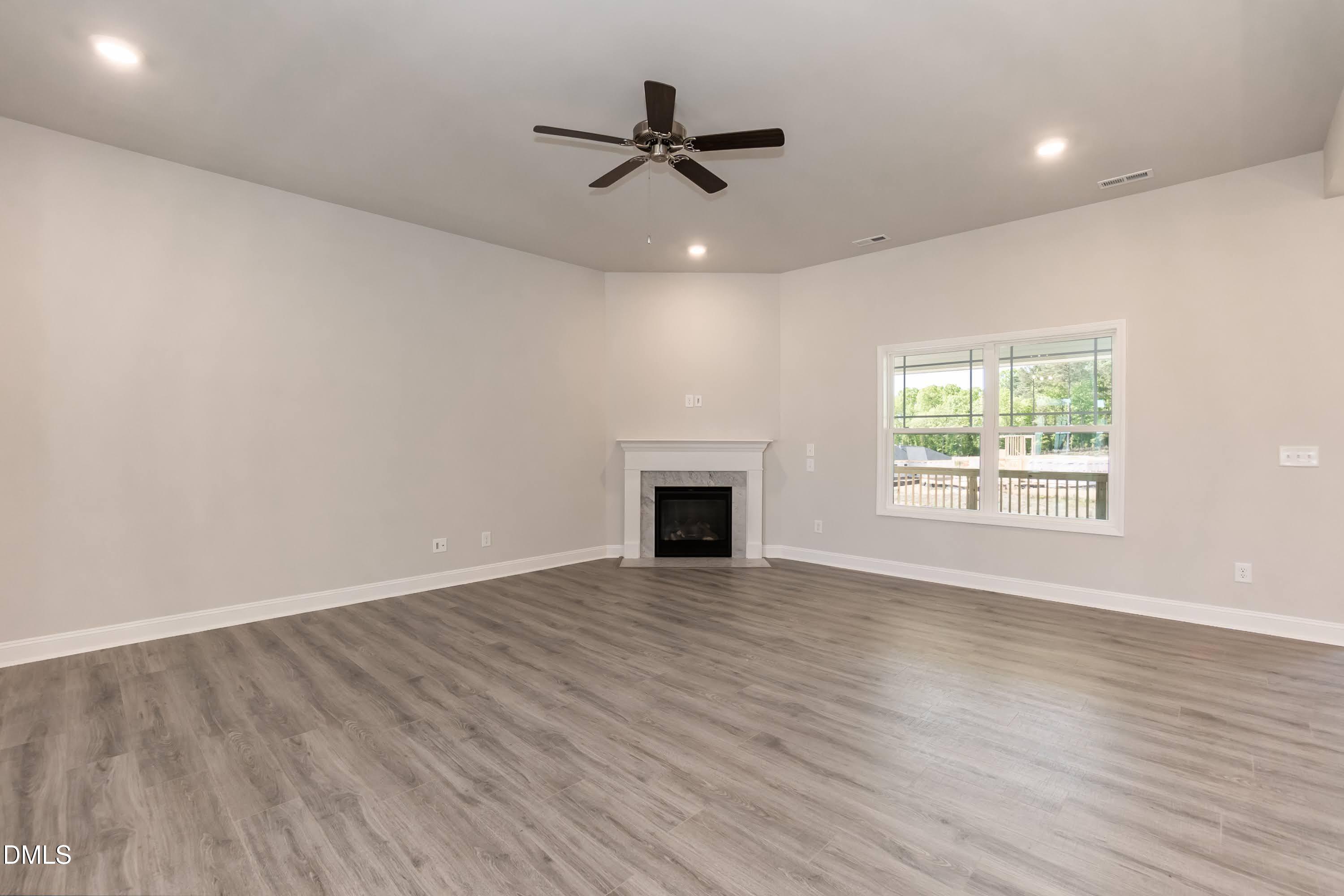 49 Galway Road Lillington, NC 27546 - Photo 8 of 39 an empty room with windows and a ceiling fan with wooden floor