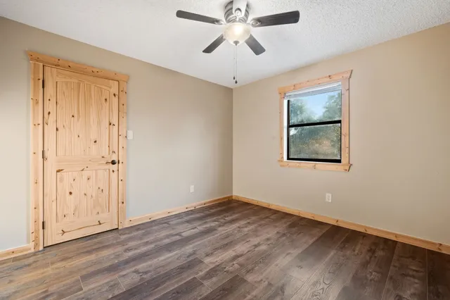 an empty room with wooden floor ceiling fan and windows