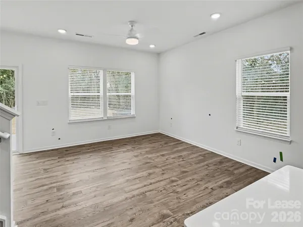an empty room with wooden floor and windows