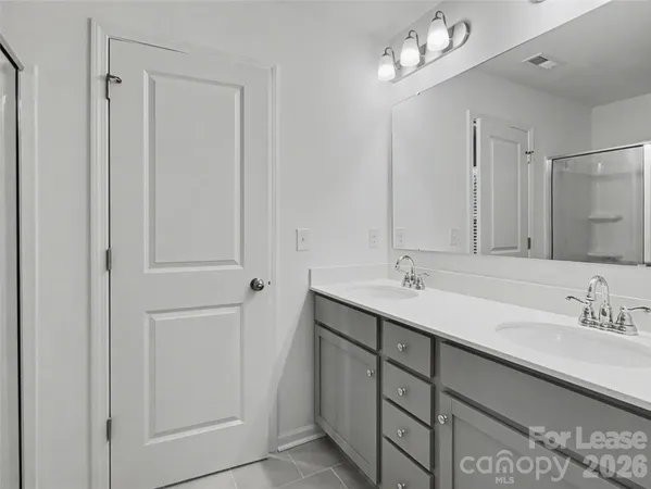 a bathroom with a double vanity sink a mirror and a bathtub