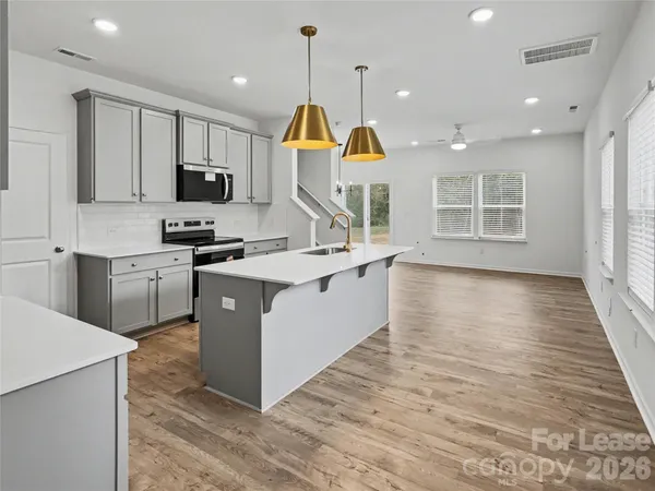 a kitchen with stainless steel appliances granite countertop a sink a stove and a wooden floors