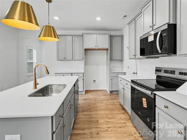 a kitchen with stainless steel appliances granite countertop a sink and a stove top oven with wooden floor