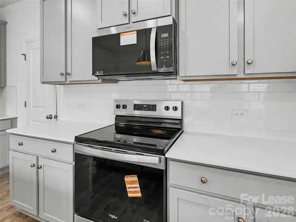 a kitchen with stainless steel appliances granite countertop white cabinets stove top oven and microwave