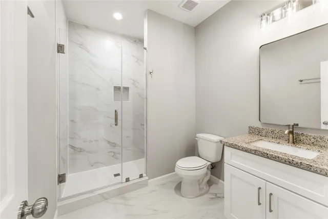 a bathroom with a granite countertop sink a toilet and shower