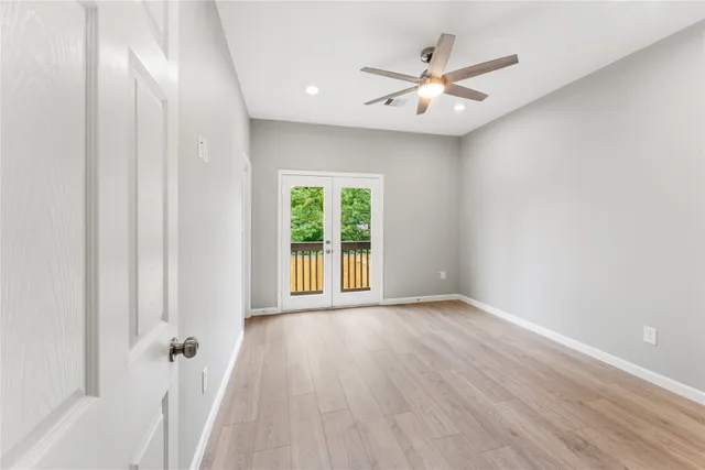 an empty room with wooden floor fan and windows