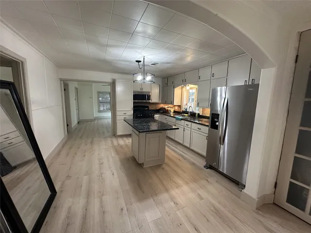 a kitchen with stainless steel appliances a refrigerator a sink dishwasher a stove and white countertops with wooden floor