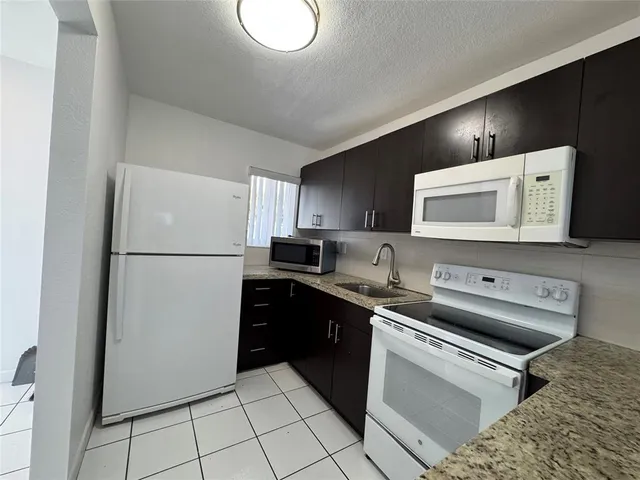 a kitchen with a refrigerator sink and cabinets