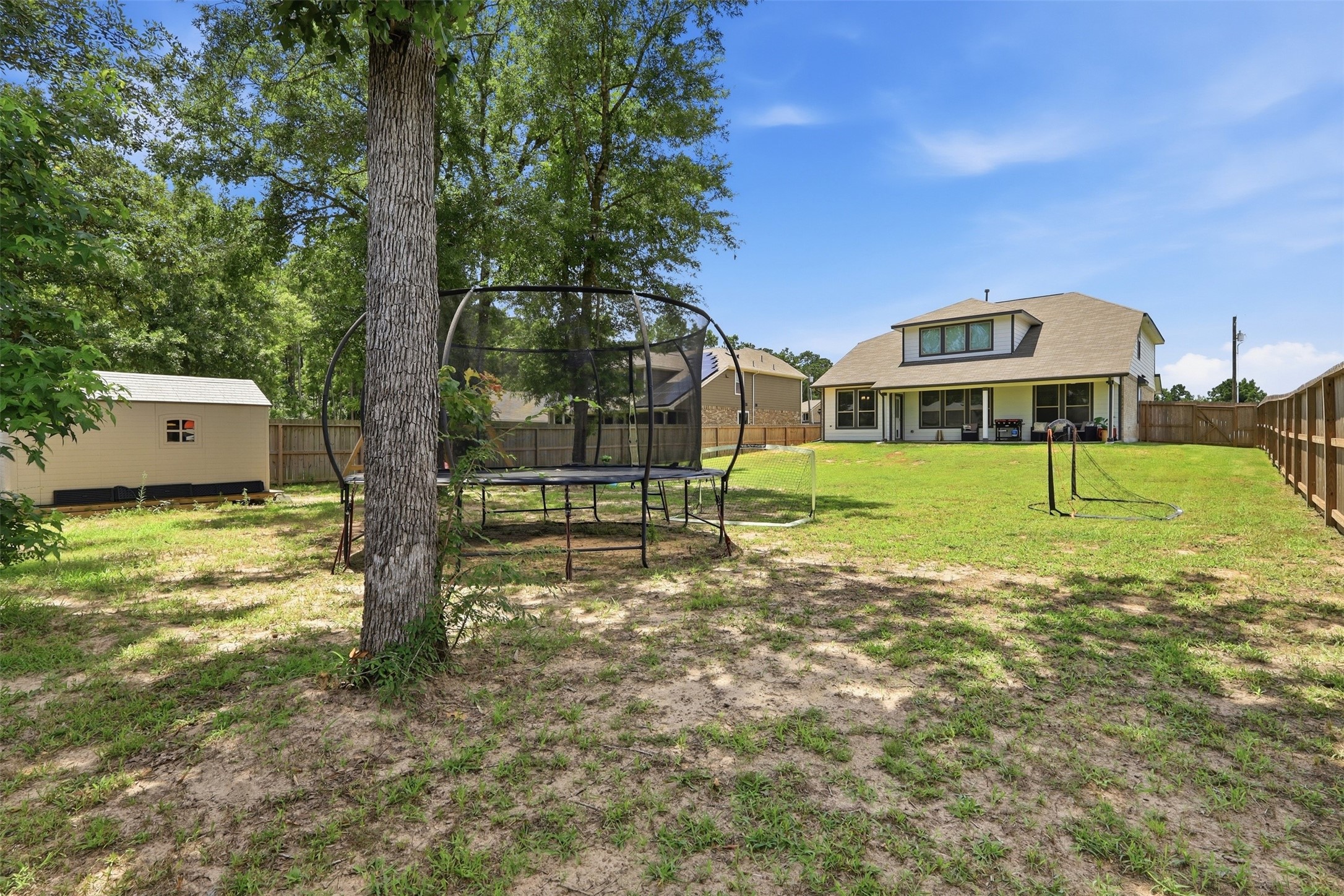 6310 Fawn Path Drive Conroe, TX 77303 - Photo 31 of 41 Expansive fenced backyard featuring a covered patio, storage shed, and playset, which come with the home. Plenty of space to entertain, play, and enjoy outdoor living.