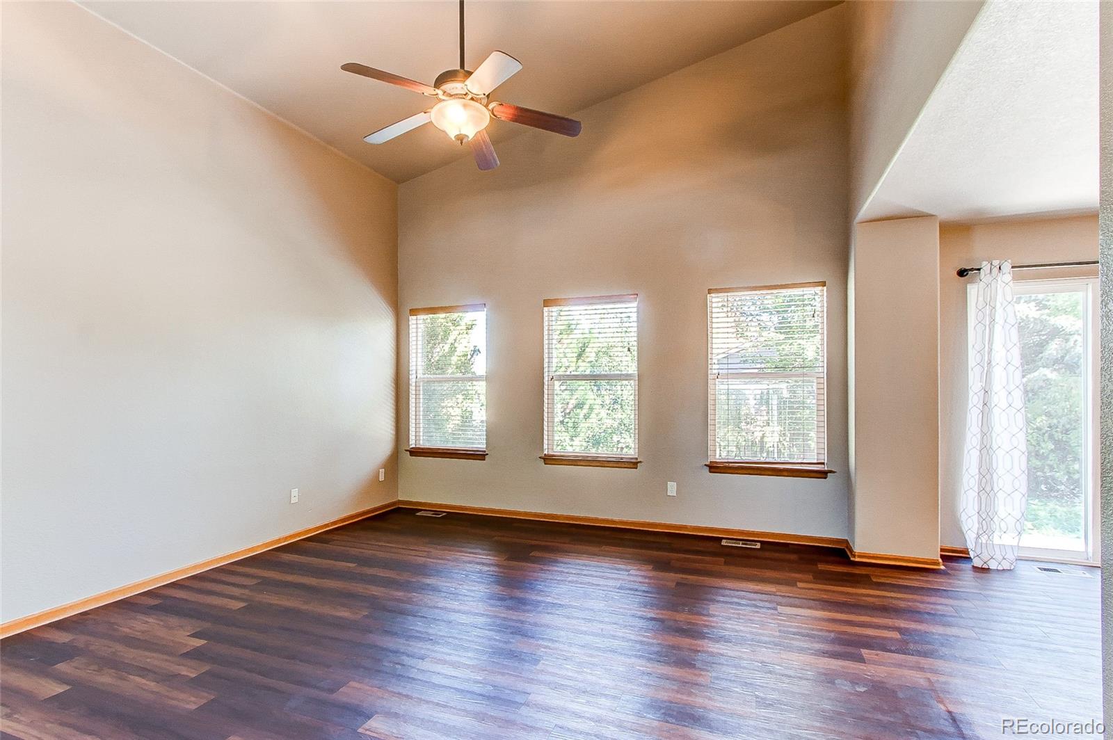 9776 Gatesbury Circle Highlands Ranch, CO 80126 - Photo 3 of 24 an empty room with wooden floor and windows