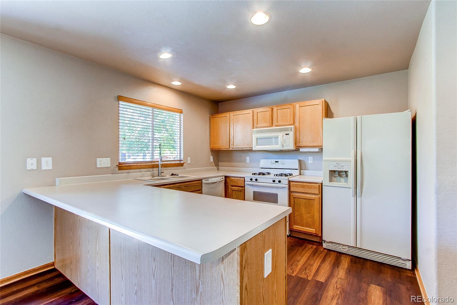 9776 Gatesbury Circle Highlands Ranch, CO 80126 - Photo 7 of 24 a kitchen with refrigerator cabinets and wooden floor
