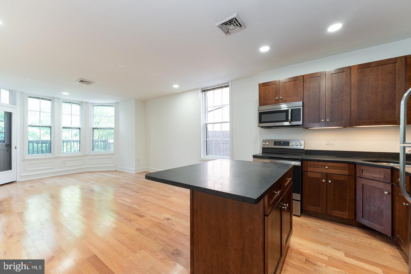 2118 Spruce Street, Unit 2R Philadelphia, PA 19103 - Photo 4 of 25 a kitchen with kitchen island granite countertop a stove top oven a sink dishwasher a dining table and chairs with wooden floor