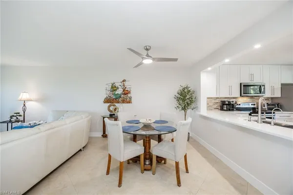 a white kitchen with a sink a stove a dining table and chairs