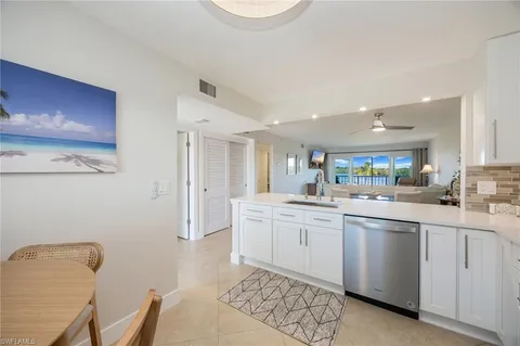 a kitchen with white cabinets and sink
