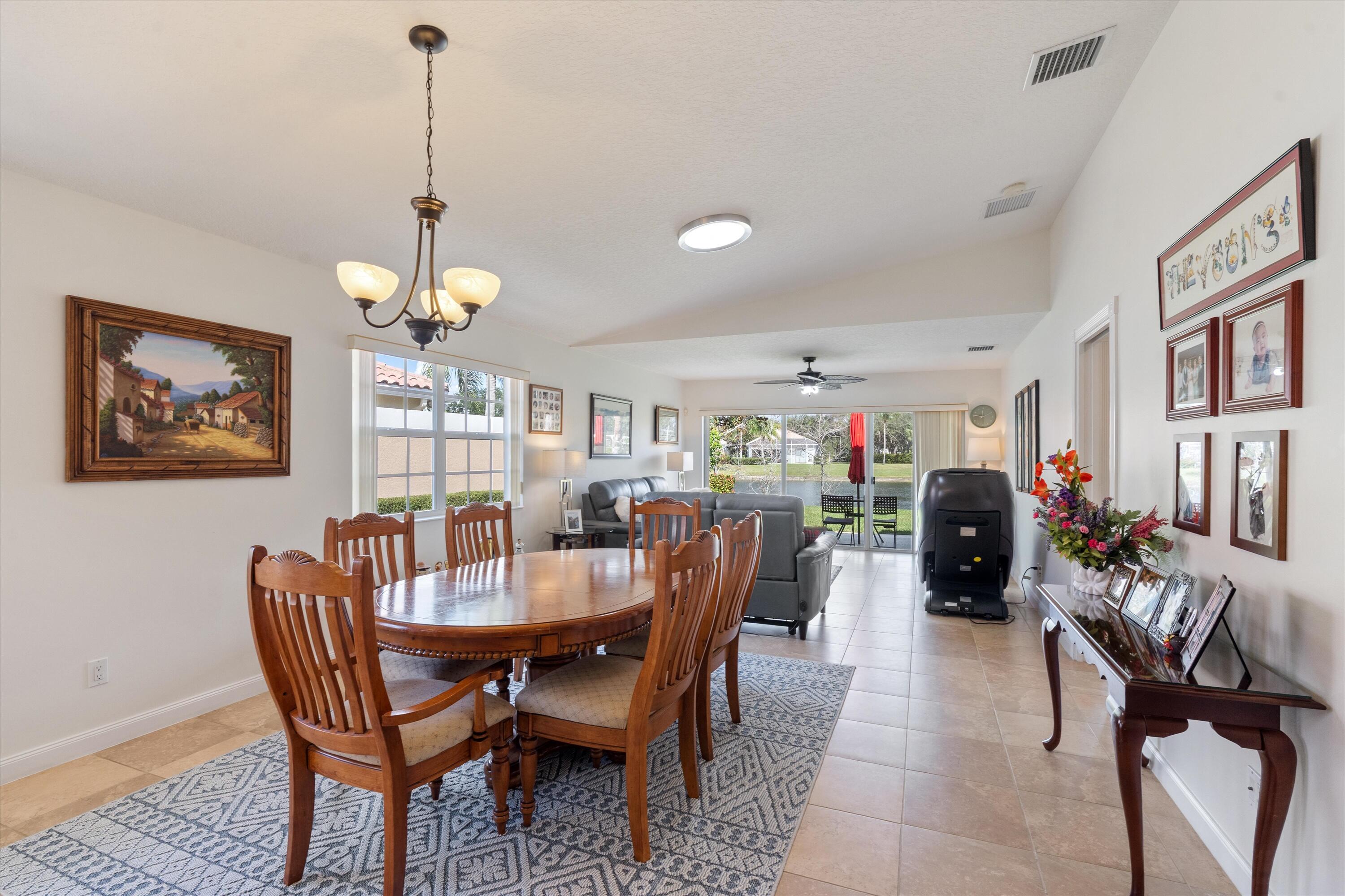 8255 Quito Place Wellington, FL 33414 - Photo 9 of 23 a dining room with furniture a rug and a chandelier