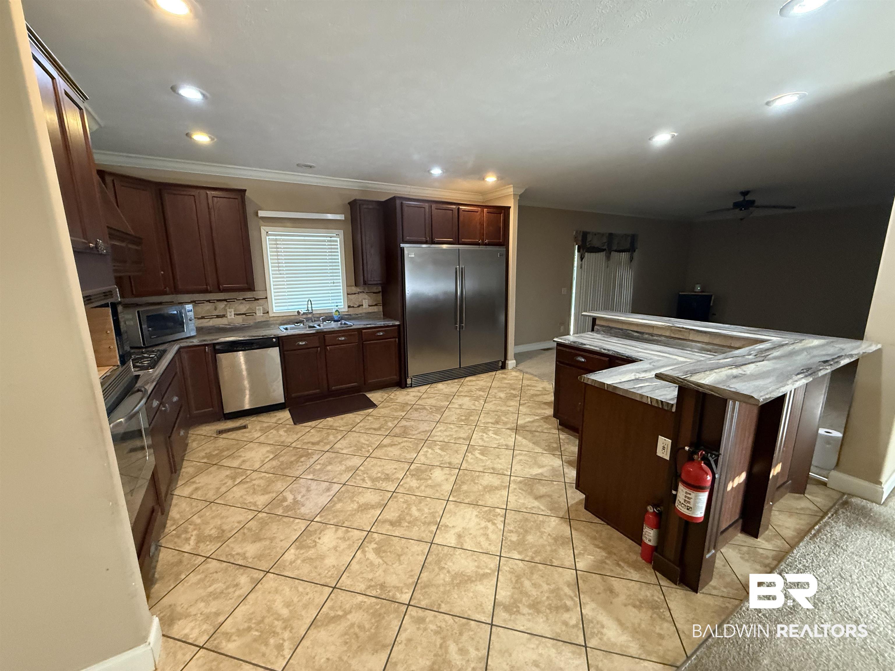 1274 Caney Loop Lillian, AL 36549 - Photo 9 of 19 Kitchen with stainless steel appliances, light tile patterned floors, dark wood finish cabinetry, ceiling fan, and recessed lighting