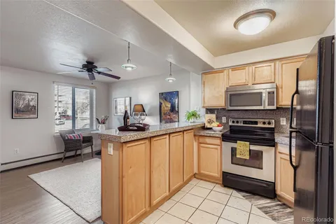 a kitchen with stainless steel appliances granite countertop a stove top oven a sink dishwasher a refrigerator and white cabinets with wooden floor