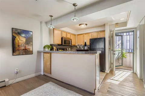 a kitchen with stainless steel appliances kitchen island granite countertop a refrigerator oven a sink dishwasher and white cabinets with wooden floor