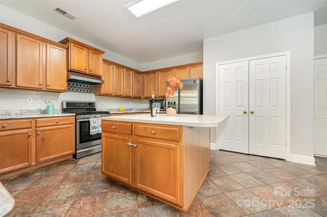 a kitchen with stainless steel appliances granite countertop a stove a sink and a refrigerator