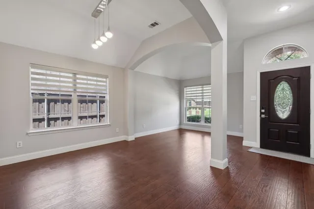 an empty room with wooden floor cabinet and windows