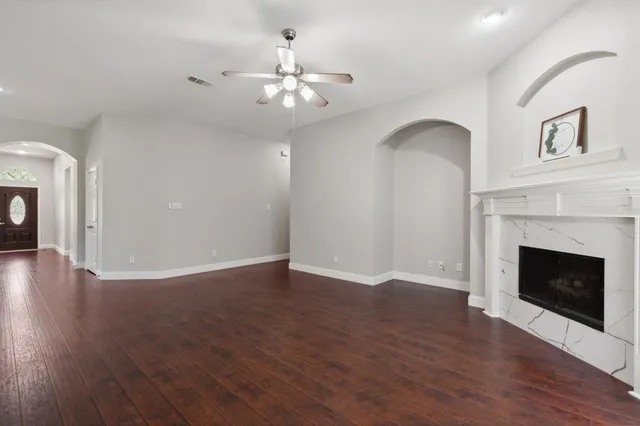 a view of an empty room with wooden floor and fireplace