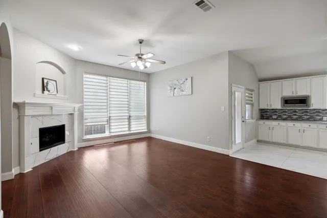 a view of an empty room with kitchen and fireplace