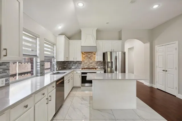 a large kitchen with stainless steel appliances lots of white cabinets