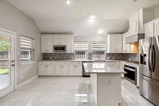 a kitchen with white cabinets and appliances