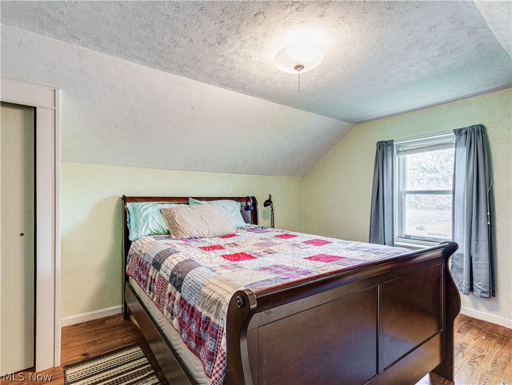 850 Ridgeview Drive Independence, OH 44131 - Photo 18 of 20 Bedroom featuring lofted ceiling, hardwood / wood-style flooring, and a textured ceiling