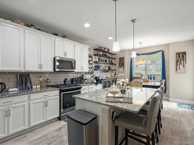 a kitchen with granite countertop a sink dishwasher stove and refrigerator with wooden floor