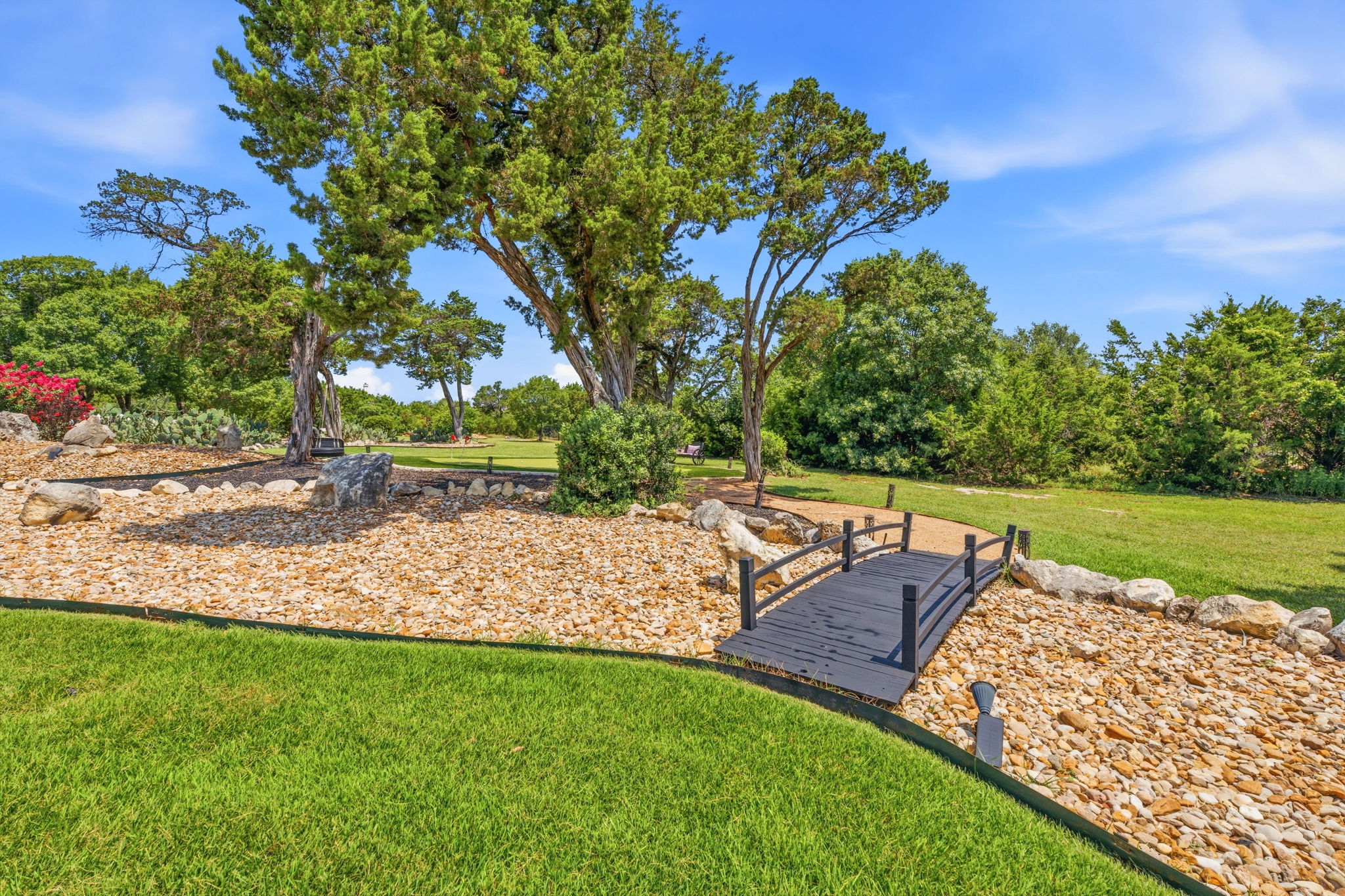 816 Brave Face Street Leander, TX 78641 - Photo 32 of 40 A charming footbridge spans a rock garden, leading to a vast, verdant lawn and mature trees.