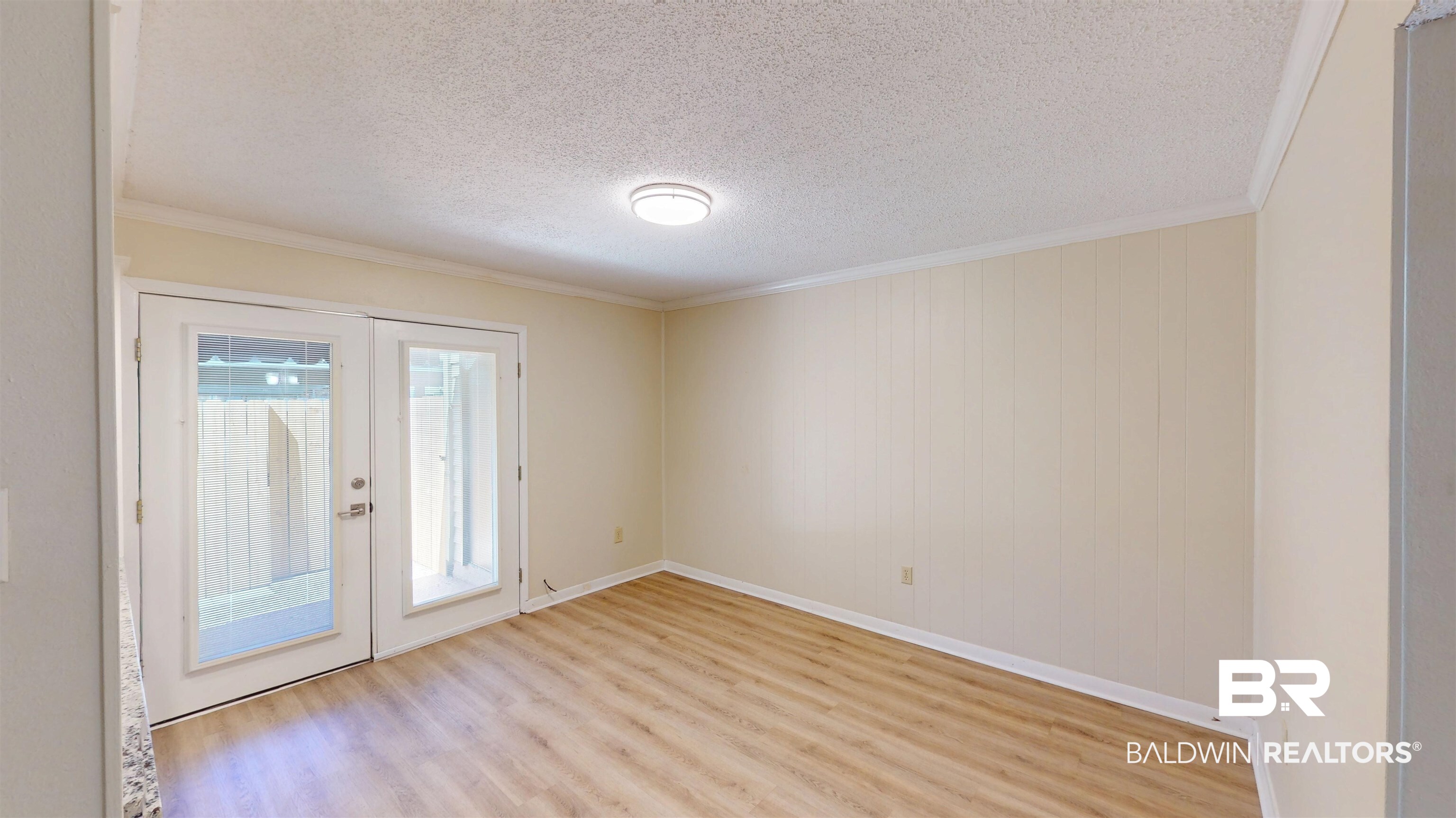 2901 Grant Street, Unit 902 Mobile, AL 36606 - Photo 9 of 35 Unfurnished room with french doors, light wood-style floors, a textured ceiling, and crown molding