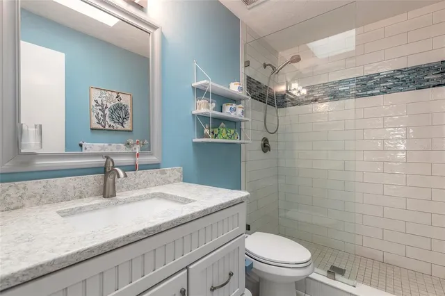a bathroom with a granite countertop sink a toilet and a mirror