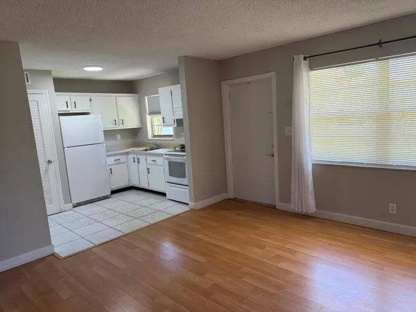 a view of a kitchen with wooden floor and white cabinets
